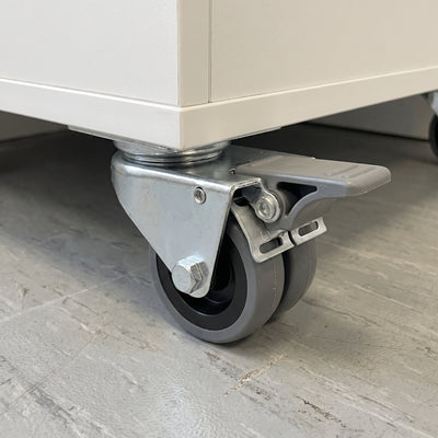 50mm twin wheel total lock top plate castor with grey rubber wheels fitted under a white mobile storage cabinet