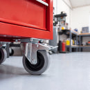 100mm braked castor with grey rubber wheel bolted under a red tool cabinet in a garage