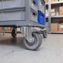 100mm braked top plate castor with grey TPR wheel under a grey steel stockroom trolley holding tote boxes