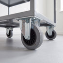 100mm fixed top plate castor with grey rubber wheel bolted under a grey steel stockroom trolley