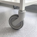 Close-up of 100mm grey plastic swivel bolt hole castor with grey TPR wheel fixed by one bolt under a white laboratory trolley