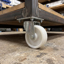 100mm swivel castor with white nylon wheel bolted with nuts under a workshop workbench