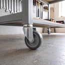 100mm swivel bolt hole castor with grey rubber wheel fitted to a mobile workbench leg in a workshop