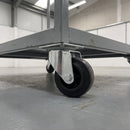 100mm swivel top plate castor with black rubber wheel bolted under a grey steel warehouse trolley
