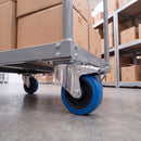 125mm blue non-marking braked swivel castor bolted under a warehouse platform trolley
