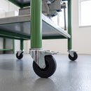 125mm black rubber braked bolt hole castor fitted to a green steel workbench leg