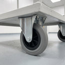 125mm fixed top plate castor with grey ribbed rubber wheel bolted under a white catering trolley on a resin floor