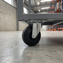 125mm swivel top plate castor with black rubber wheel bolted under a steel warehouse trolley