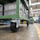 160mm braked castor with black rubber wheel under a green steel industrial trolley carrying parts bins in a factory