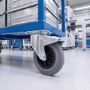 160mm braked castor with grey rubber wheel under a blue steel platform truck on an assembly line