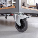 160mm braked castor with grey rubber wheel bolted under a mobile workbench in a garage