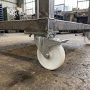 160mm braked castor with white nylon wheel bolted with nuts under a steel industrial trolley