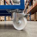 160mm braked castor with white nylon wheel bolted under a blue warehouse cart