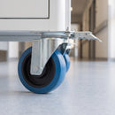 160mm directional lock castor with blue non-marking rubber wheel and lock catch fitted under a white hospital equipment trolley