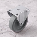 160mm fixed castor with grey TPR wheel and steel top plate on light grey marble, high angle view