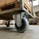 160mm fixed castor with grey TPR wheel and steel top plate under a timber pallet trolley in a warehouse