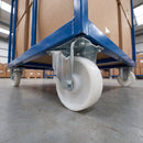 160mm fixed castor white nylon wheel fitted under a blue warehouse trolley loaded with boxes