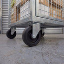 160mm fixed top plate castor with ribbed black rubber wheel under a galvanised cage trolley in a loading bay