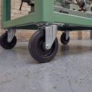 160mm fixed top plate castor with ribbed black rubber wheel under a green steel workshop machine stand