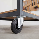 160mm swivel castor with black rubber wheel bolted under a steel mobile workbench in a garage workshop