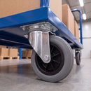 160mm swivel castor with grey rubber wheel bolted under a blue warehouse platform truck loaded with boxes