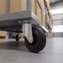 160mm swivel top plate castor with black rubber wheel bolted under a grey steel warehouse platform trolley