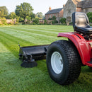 Turf tread tyre on the rear of a ride-on garden tractor pulling a lawn sweeper across estate grounds