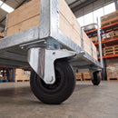 200mm braked castor with black rubber wheel under a galvanised warehouse platform truck loaded with wooden crates