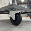 200mm braked top plate castor with large black ribbed rubber wheel and total lock pedal under a grey steel warehouse trolley