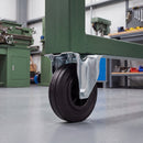 200mm fixed top plate castor with black rubber wheel under a green steel machine stand in a workshop