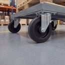 200mm fixed top plate castor with ribbed black rubber wheel under a grey steel platform trolley carrying a pallet