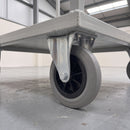 200mm fixed top plate castor with large grey ribbed rubber wheel bolted under a grey steel warehouse platform trolley
