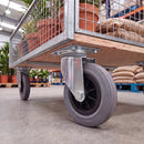 200mm swivel castor with grey rubber wheel under a mesh sided flatbed warehouse trolley