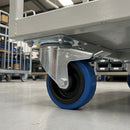 80mm braked top plate castor with blue non-marking rubber wheel bolted under a grey steel warehouse trolley
