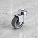 50mm swivel bolt hole castor M10 with grey rubber wheel on light grey marble, high-angle three-quarter view