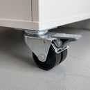 50mm twin wheel total lock top plate castor with grey foot brake fitted under a white mobile storage cabinet
