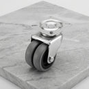 50mm twin wheel swivel top plate castor with grey rubber wheels on light grey marble, 45 degree three-quarter view from a steep high angle