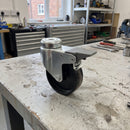 75mm braked swivel castor with black polypropylene wheel on a workshop bench showing the M10 bolt hole