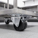 75mm twin wheel braked top plate castor bolted under a stainless steel catering trolley in a commercial kitchen