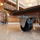 75mm twin wheel braked top plate castor bolted under a hotel luggage trolley in a hotel lobby