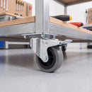 80mm braked castor with grey rubber wheel bolted under a mobile workbench in a workshop