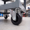 80mm fixed castor with black rubber wheel bolted under a grey steel workshop trolley