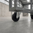 80mm swivel top plate castor with black rubber wheel bolted under a grey steel warehouse trolley
