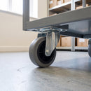 80mm swivel top plate castor with grey rubber wheel fitted under a grey steel stockroom trolley on vinyl flooring