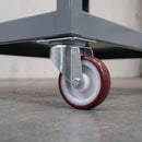 80mm swivel top plate castor with maroon polyurethane wheel under a grey steel workshop parts trolley