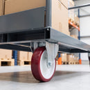 Fixed castor with red polyurethane wheel under a grey steel warehouse platform trolley