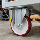 Fixed castor with red polyurethane wheel under a white steel warehouse trolley