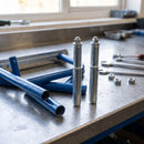 Two 25.4mm round spring fitting castor adaptors on a workshop bench beside round tube step frame parts