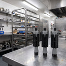 Three square expanding castor tube adaptors on a stainless steel worktop in a commercial kitchen