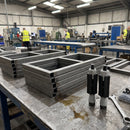 Square expanding tube adaptors beside square box-section frames on a manufacturing workbench